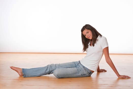 Happy teenager sitting on wooden floor