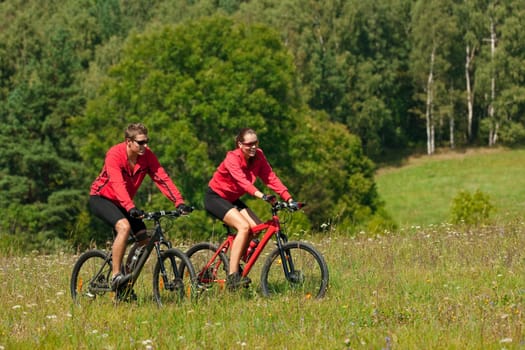 Summer - young man woman couple ride mountain bike in nature