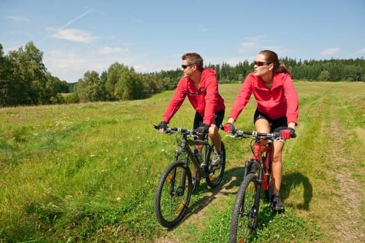 Summer - young man woman couple ride mountain bike in nature