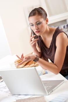 Young female designer on the phone at office