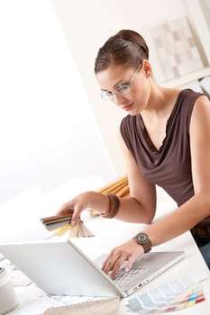 Smiling female designer with color swatch and laptop