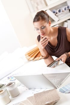 Smiling female designer with color swatch and laptop