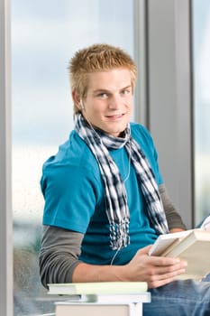 Young man with book listening music