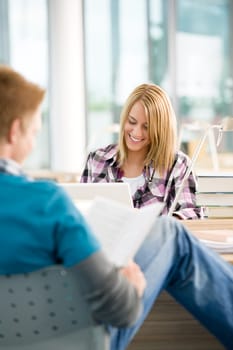 Two students with books and laptop
