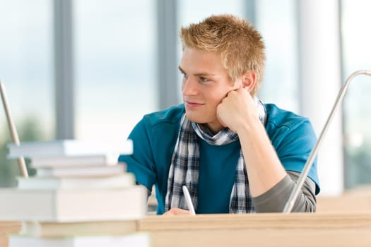 Male student with books sitting at table