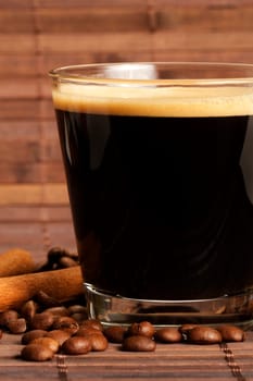 Espresso next to cinnamon and coffee beans