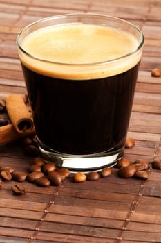 Espresso next to cinnamon and coffee beans