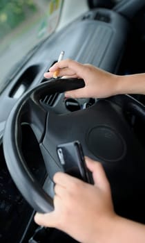 Cigarette and mobile phone on the steering wheel