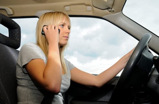 Young woman talking on the phone in the car