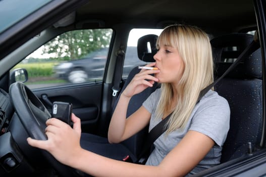 Young woman with cigarette and mobile phone in car