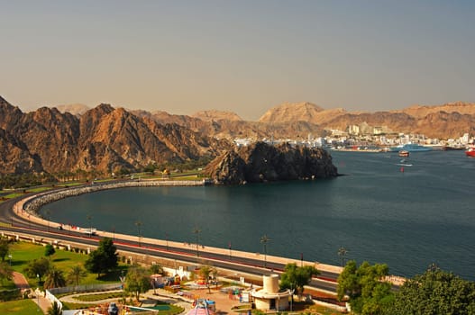 Lakeside street at the harbour basin with a view of the Muttrah district in front of the bare Be