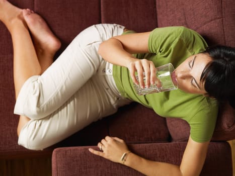 woman drinking water on sofa