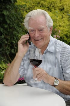 Pensioner with mobile phone and red wine