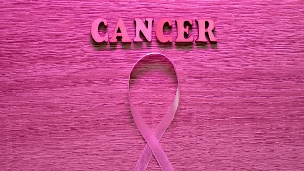 Wooden Pink Neon Background image Breast cancer Awareness is celebrated in October Month. The inscription with the symbol is a ribbon. Close-up, copy space , past text