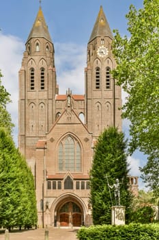 an old building with two towers on the top and one at the bottom, surrounded by green trees in front