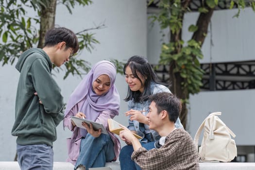 Group of Asian college student reading books and tutoring special class for exam on grass field at outdoors. Happiness and Education learning concept. Back to school concept. Teen and people theme..