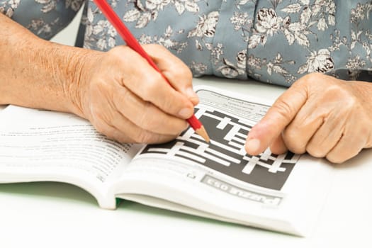 Alzheimer disease AD, Asian elderly woman playing sudoku puzzle game to practice for dementia prevention.