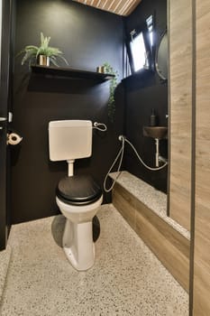 a bathroom with black walls and white flooring on the wall, there is a plant in the toilet bowl