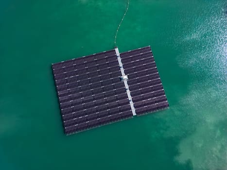 Aerial view of floating solar farm with many solar panels on turquoise lake