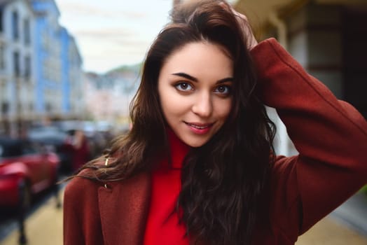 portrait of a fashionable woman posing for the camera in a brown coat and red sweater