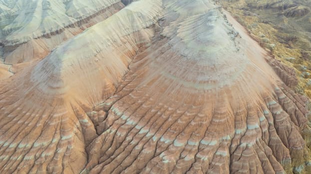 Colorful high mountains and a canyon made of clay. A large gorge with different rocks and different colors. Red, orange, white and yellow flowers of the walls of the rocks. A tourist walks. Aktau