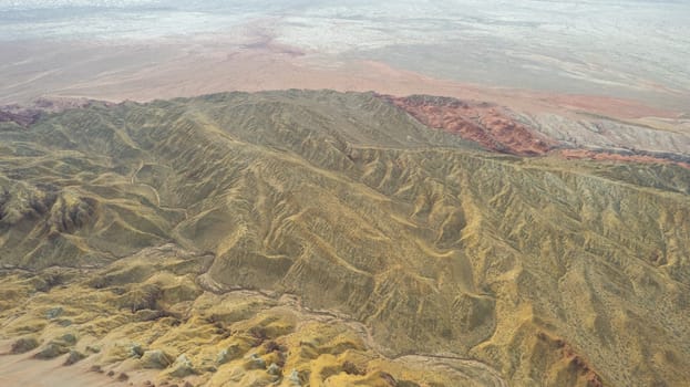 Colorful high mountains and a canyon made of clay. A large gorge with different rocks and different colors. Red, orange, white and yellow flowers of the walls of the rocks. A tourist walks. Aktau