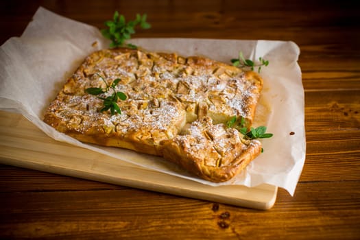 prepared curd semolina pie with quince inside and covered with powdered sugar on a wooden board.
