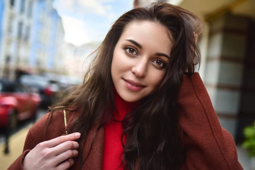 portrait of a fashionable woman posing for the camera in a brown coat and red sweater