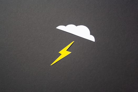 White cut out paper cloud and yellow lightning on black background. weather concept. Energy and electricity. Nature
