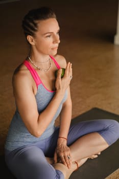 A woman does self - massage with a small ball while sitting in a fitness room . Myofascial relaxation.