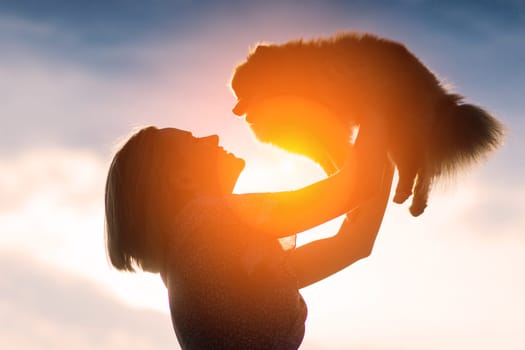 Close up portrait of smiling young attractive woman embracing Pomeranian spitz.
