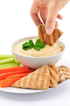 Hand dipping pita in hummus