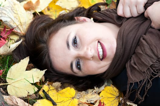Young woman lying in autumn leaves