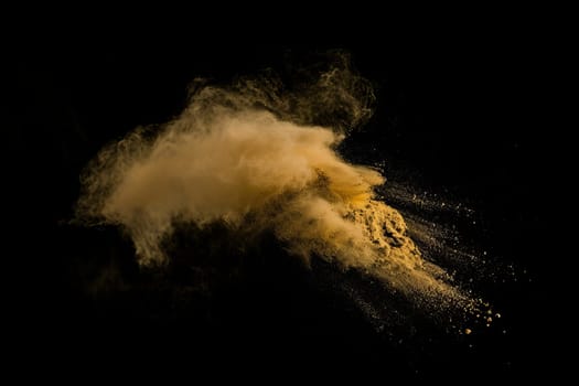 Golden powder explosion against black background.