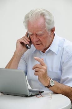 Pensioner with mobile phone and netbook