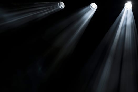 Dramatic stage spotlight illumination with three beams in dark setting.