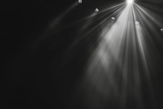 Bright spotlight rays shining in dark theater stage environment.