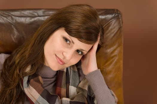 Hispanic woman on brown leather armchair