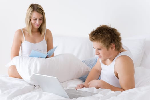 Young couple relax in bed with laptop