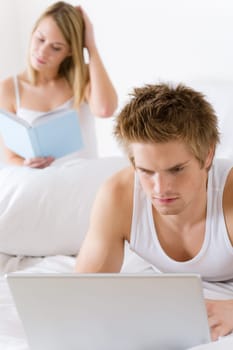 Young couple relax in bed with laptop