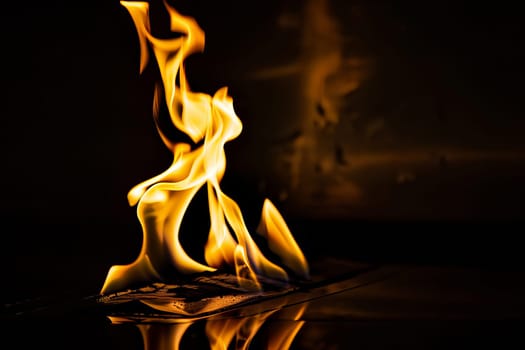 Dramatic flames engulfing paper with fiery glow in dark room.
