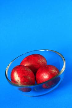 three red easter eggs in glass bowl