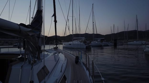 Sailboats anchored in tranquil sunset harbor with calm waters.