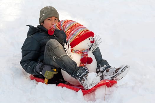 Child with snowman and toboggan