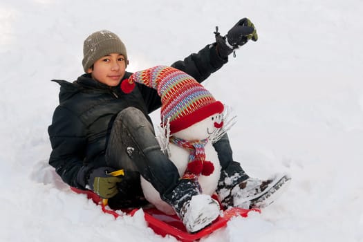 Child with snowman and toboggan