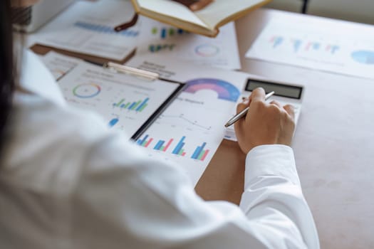 Businesswoman using a calculator to calculate numbers on a company's financial documents, she is analyzing historical financial data to plan how to grow the company. Financial concept.