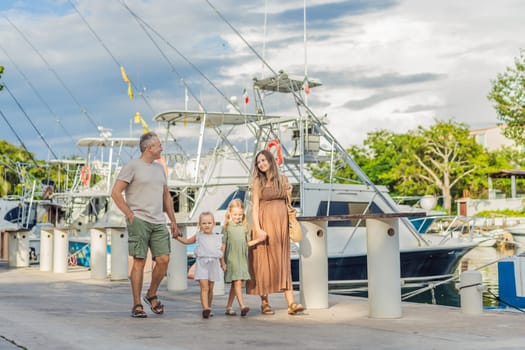 A happy, mature couple over 40 with their two daughters enjoying a leisurely walk on the waterfront, their joy evident as they embrace the journey of pregnancy later in life.