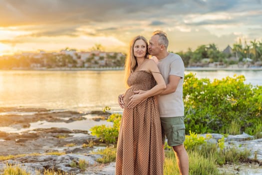 A happy, mature couple over 40, enjoying a leisurely walk on the waterfront On the Sunset, their joy evident as they embrace the journey of pregnancy later in life.