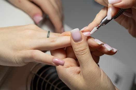 Female hands and tools for manicure, process of performing manicure in beauty salon. Nail care procedure in a beauty salon. Gloved hands of a skilled manicurist cutting cuticles. Concept spa body care