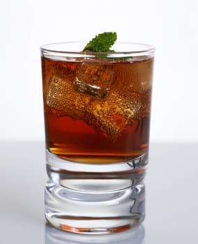 Cocktail whiskey cola with ice and mint in a glass isolated on white background